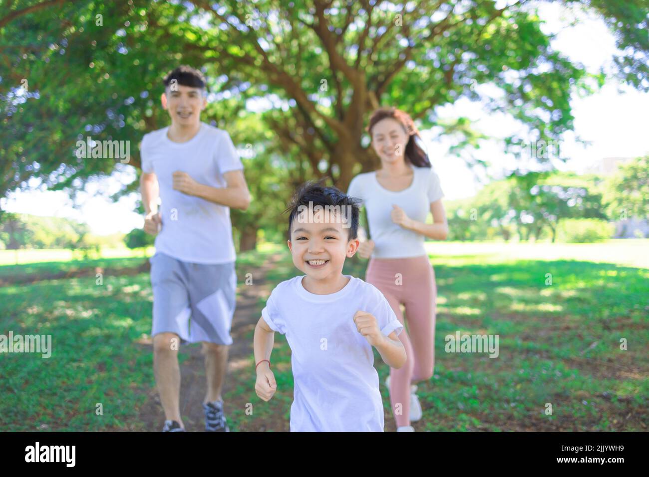 Feliz niño jogging con los padres en el parque de la ciudad Foto de stock