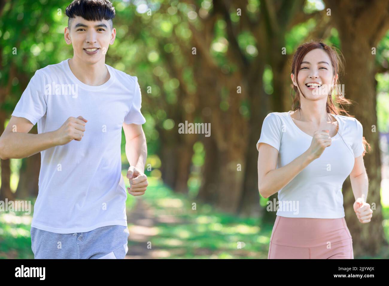 joven pareja corriendo juntos en el parque en un día soleado Foto de stock
