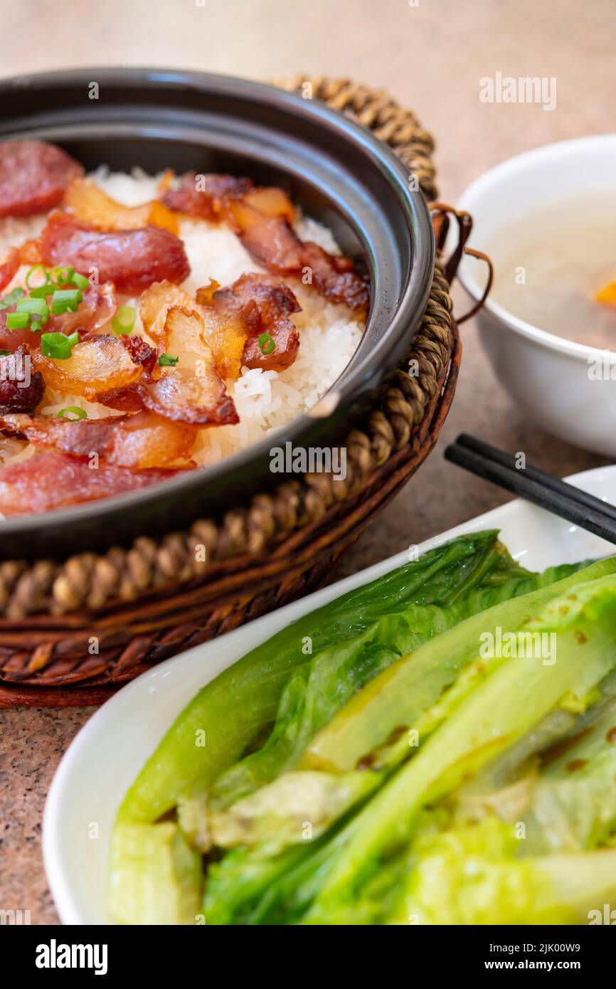 Ángulo de visión de arroz de arcilla olla de salchicha de estilo chino y tocino secado al aire con sopa y composición vertical de repollo Foto de stock
