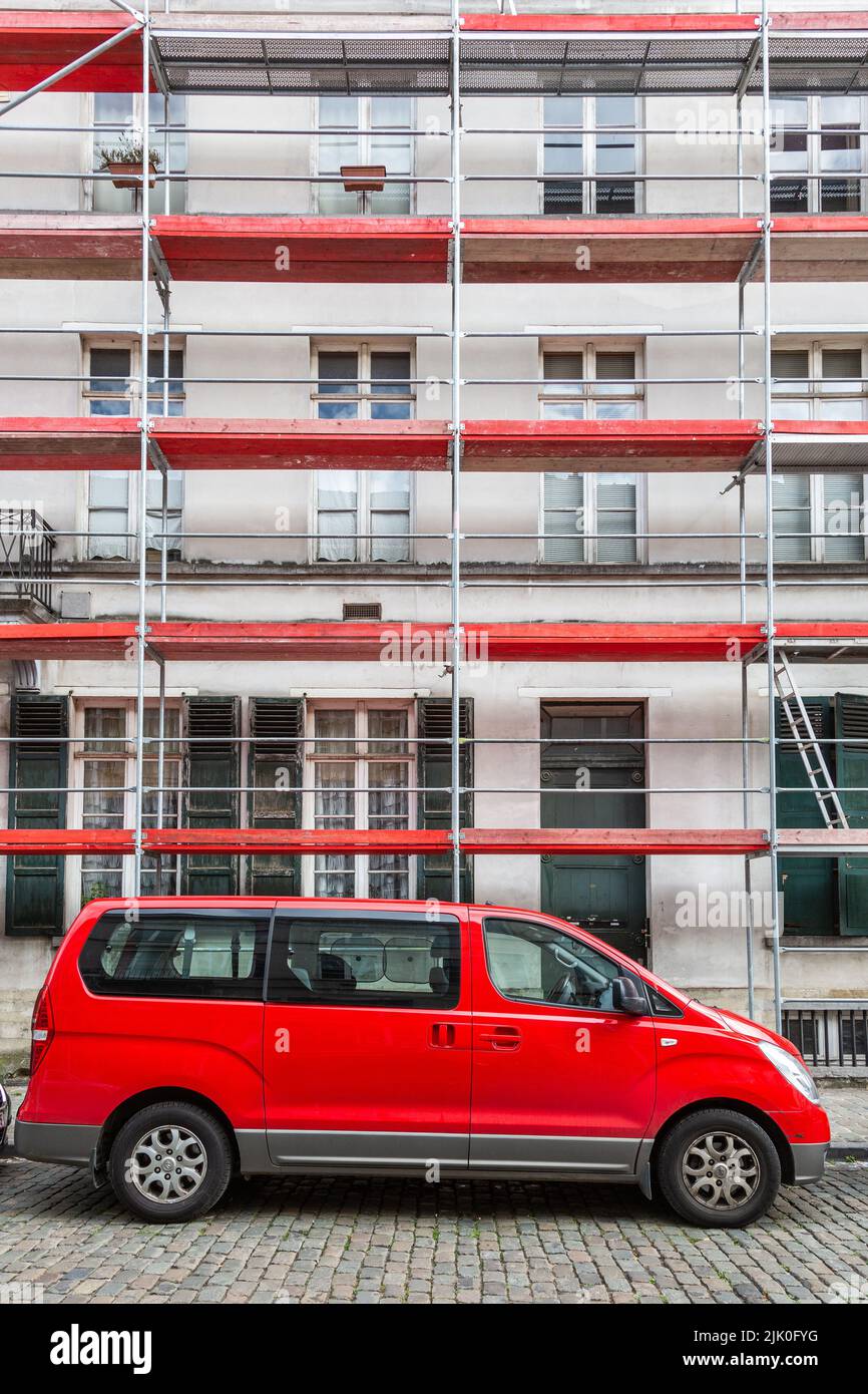 Minivan estacionado frente a andamios con aviones horizontales rojos. Foto de stock
