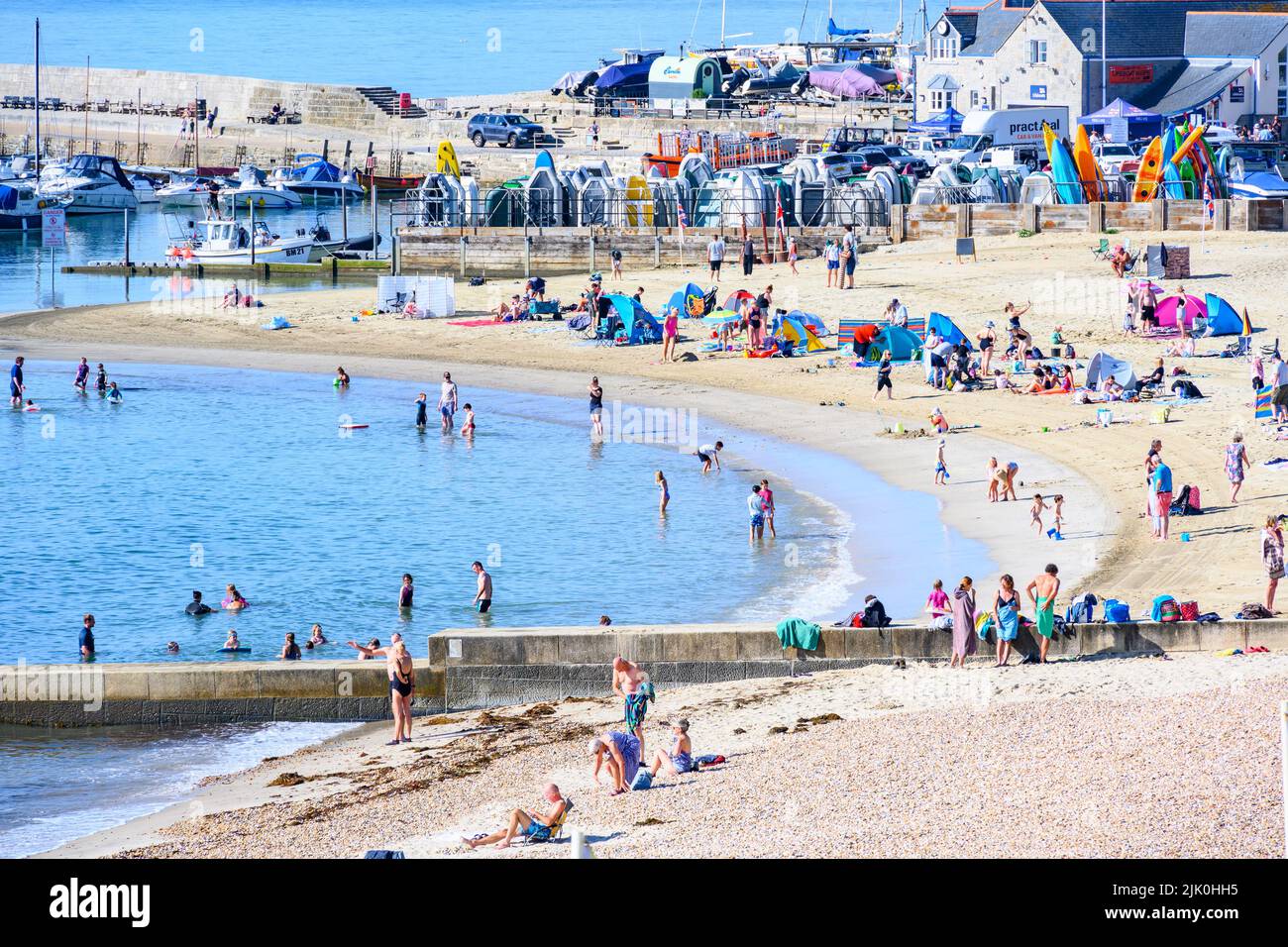 Lyme Regis, Dorset, Reino Unido. 29th de julio de 2022. Clima en el Reino Unido: Las multitudes acuden a la playa en el centro turístico costero de Lyme Regis para disfrutar de un sol abrasador y caluroso. Las familias, los turistas y los que buscan sol salieron temprano para asegurarse un lugar en la playa para empaparse del tiempo soleado, ya que hace un bienvenido regreso este fin de semana. Crédito: Celia McMahon/Alamy Live News Foto de stock