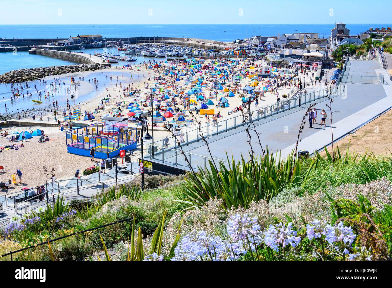 Lyme Regis, Dorset, Reino Unido. 29th de julio de 2022. Clima en el Reino Unido: Las multitudes de turistas y bañistas acuden a la playa abarrotada de la localidad costera de Lyme Regis para disfrutar del sol abrasador. Las familias, los turistas y los que buscan sol se empaparon del precioso clima soleado, ya que hizo un bienvenido regreso a tiempo para el fin de semana. Crédito: Celia McMahon/Alamy Live News Foto de stock