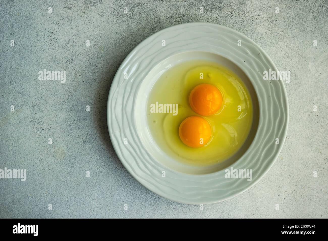 Huevos crudos con yema y blancos en el recipiente Foto de stock