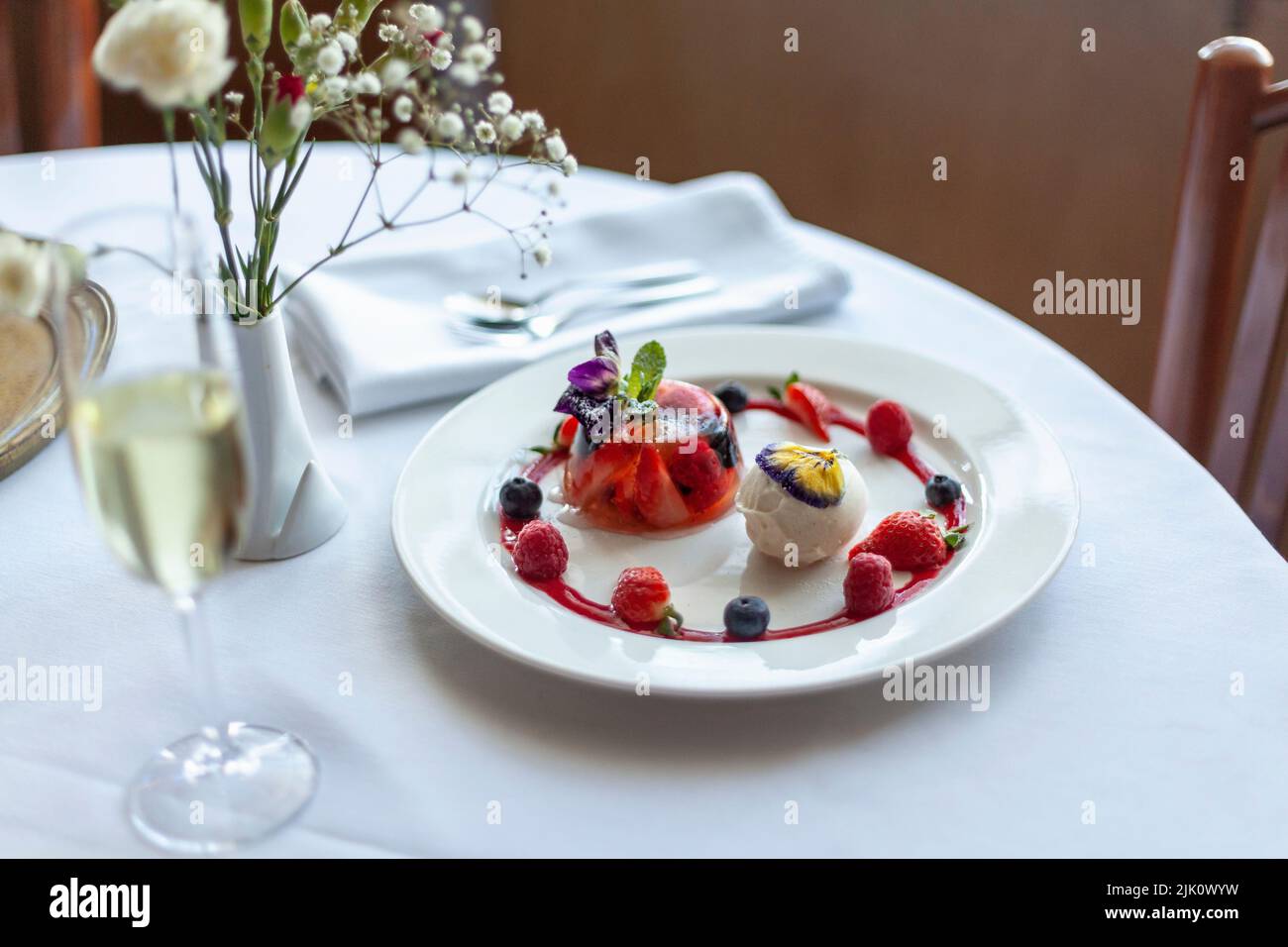 Gelatina con bayas y helado de vainilla con flores comestibles Foto de stock