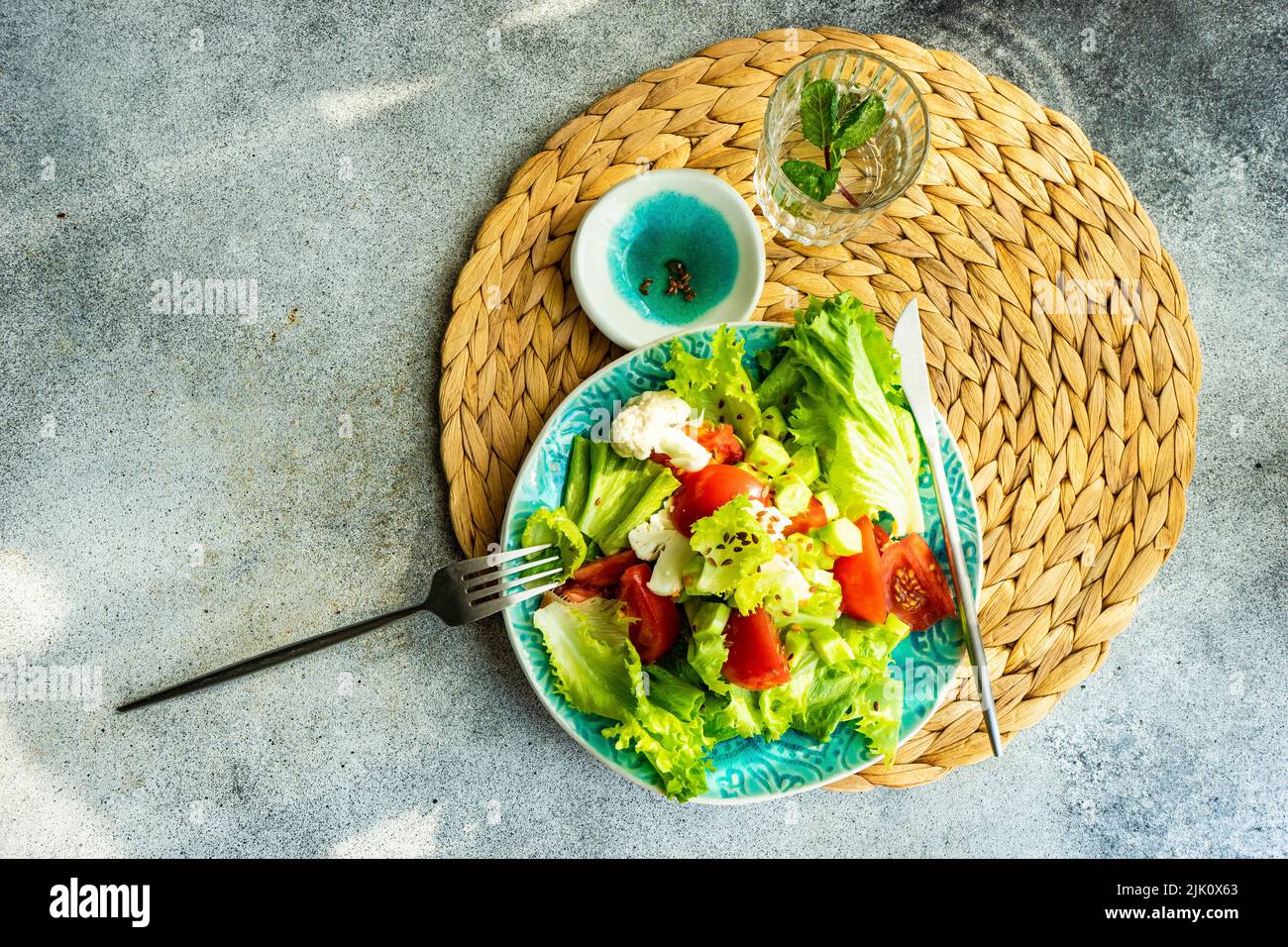 Cuenco con ensalada de verduras crudas con semillas de lino servido sobre mesa de hormigón Foto de stock