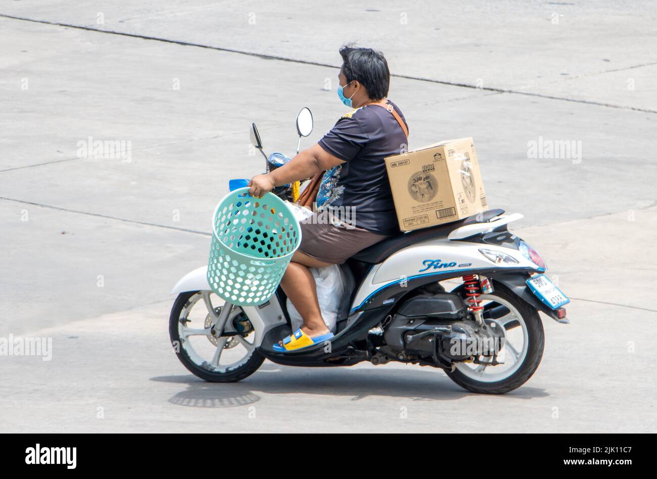 SAMUT PRAKAN, TAILANDIA, 29 2022 DE MARZO, Un hombre monta una motocicleta con una carga Foto de stock