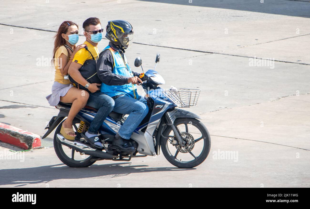 SAMUT PRAKAN, TAILANDIA, 30 2022 DE MAYO, un taxista en una motocicleta viaja con una pareja. Foto de stock
