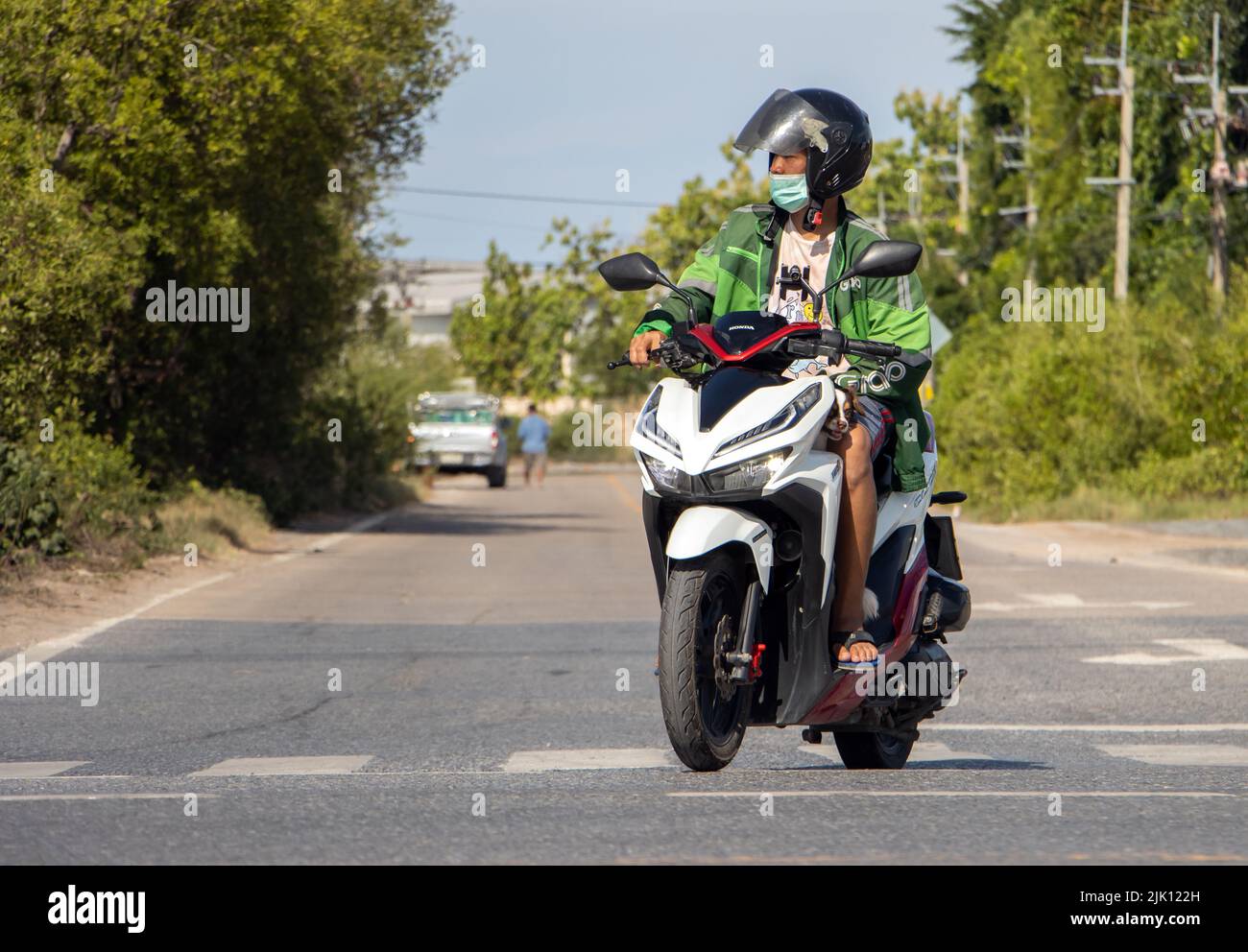 BANGKOK, TAILANDIA, 05 2022 DE JUNIO, Un hombre con casco monta una motocicleta en la carretera rural Foto de stock