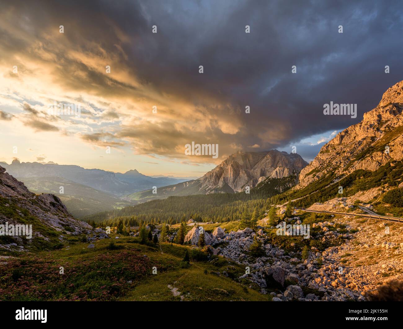 Puesta de sol sobre la montaña de Conturines con nubes de colores en el cielo y la luz dorada sobre los pinos y en el valle, Dolomitas, Italia, Europa Foto de stock