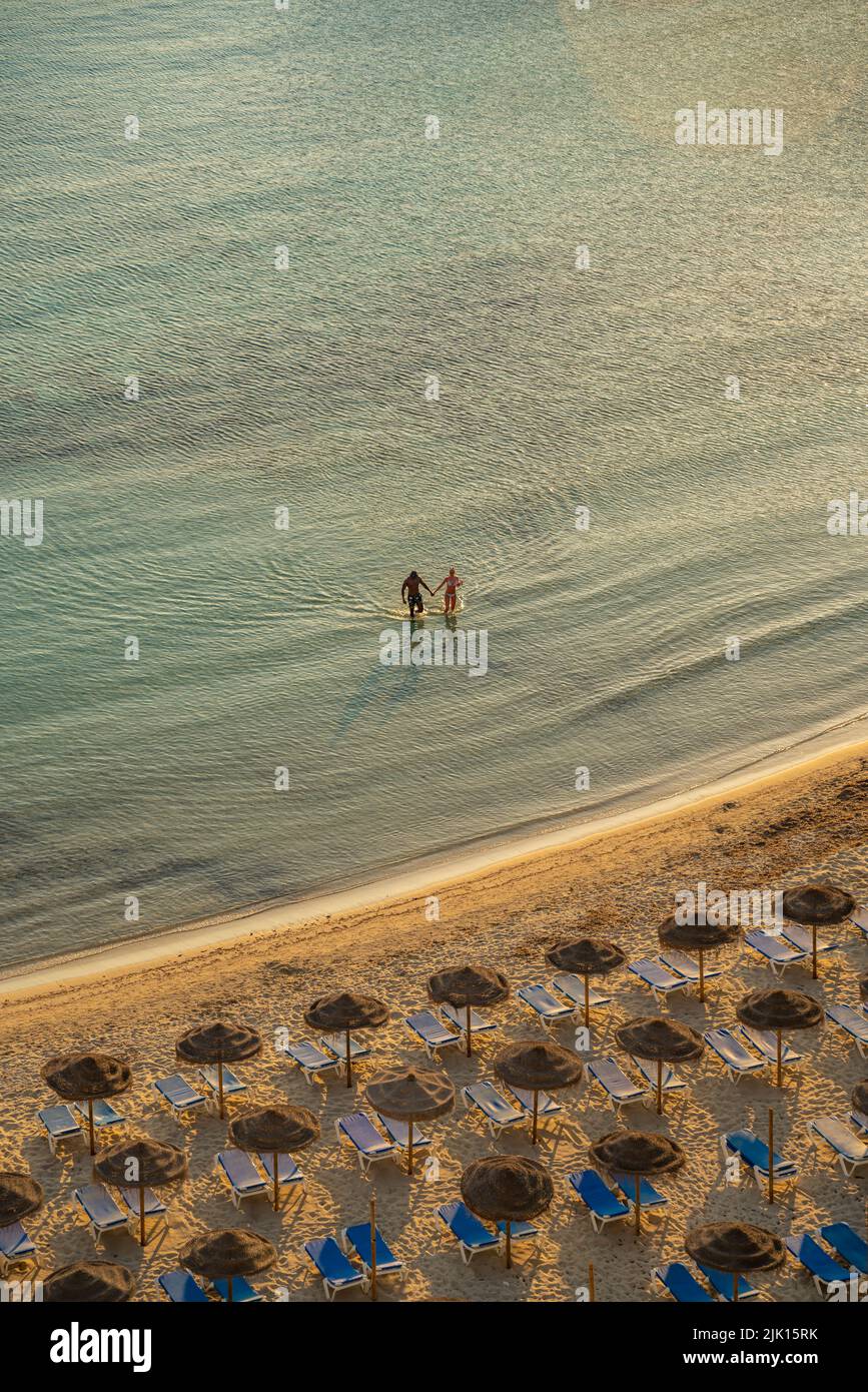 Vista de pareja en el mar y sombrillas en Platja de Cala Galdana en Cala Galdana, Cala Galdana, Menorca, Islas Baleares, España, Mediterráneo, Europa Foto de stock