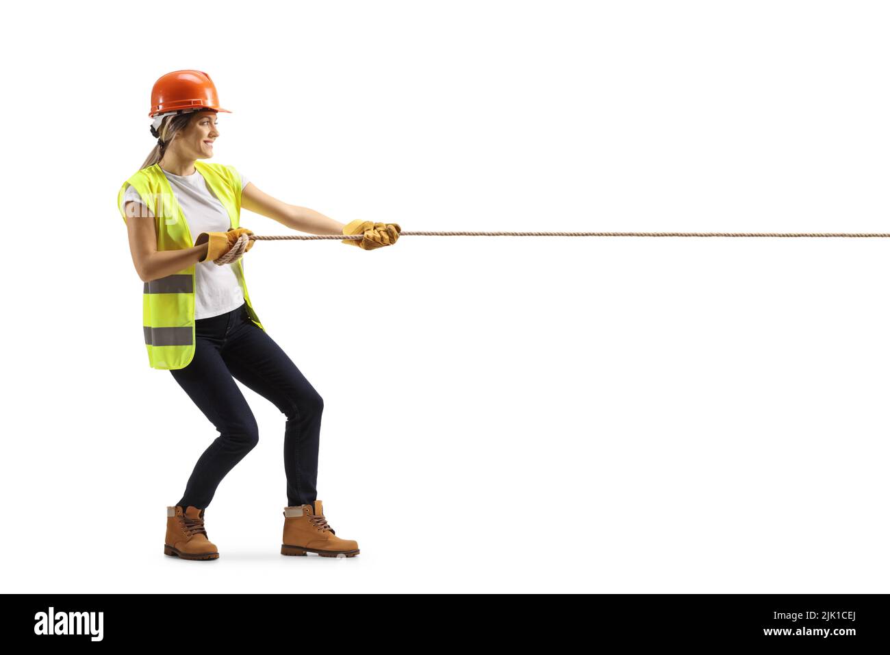 Plano de perfil completo de una mujer ingeniera tirando de una cuerda aislada sobre fondo blanco Foto de stock