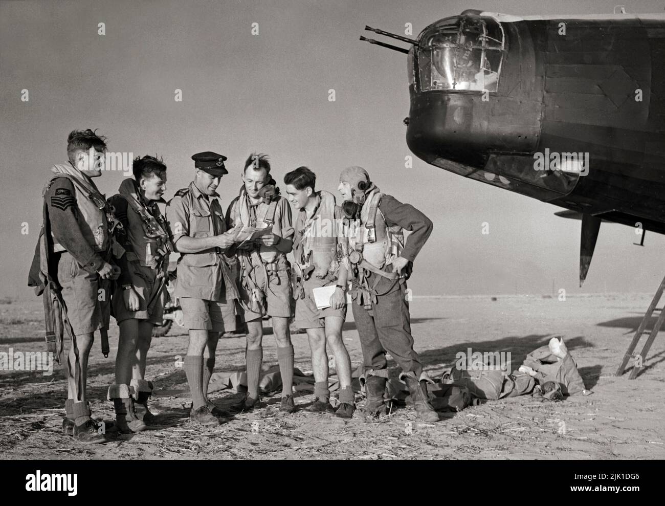 La tripulación de un Vickers Wellington Mark X del Escuadrón 150 de la RAF recibe una información final de su comandante de vuelo antes de despegar de Kairouan, Túnez, para una incursión en objetivos en el área de Salerno el día antes de los aterrizajes Aliados. El Wellington fue un bombardero medio de largo alcance bimotor británico diseñado a mediados de los años 1930s, utilizado como bombardero nocturno en los primeros años de la Segunda Guerra Mundial, hasta que fue reemplazado por los 'heavies' de cuatro motores más grandes, como el Avro Lancaster. Tiene la distinción de haber sido el único bombardero británico producido durante la guerra. Foto de stock