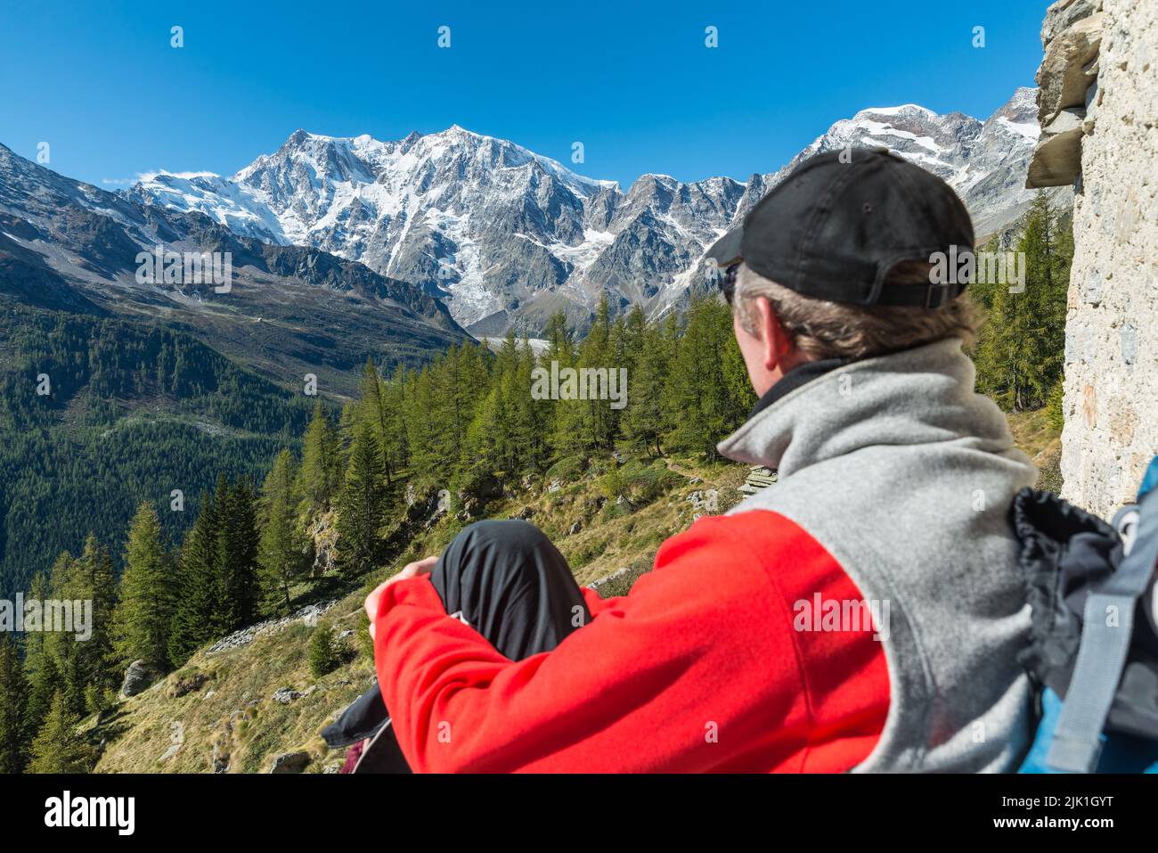 Alpes italianos y excursionista descansando mientras admira las vistas. Macugnaga, Italia. Concepto de senderismo, deportes y actividades al aire libre Foto de stock