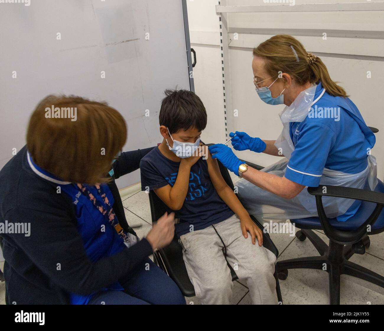 Niño recibiendo la vacuna COVID del personal del NHS, Reino Unido Foto de stock