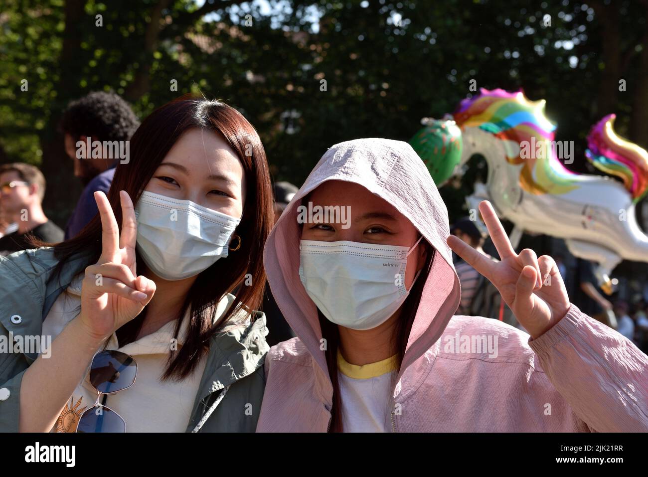 Dos mujeres felices llevando máscaras en una multitud en el festival del puerto de Bristol, Reino Unido Foto de stock