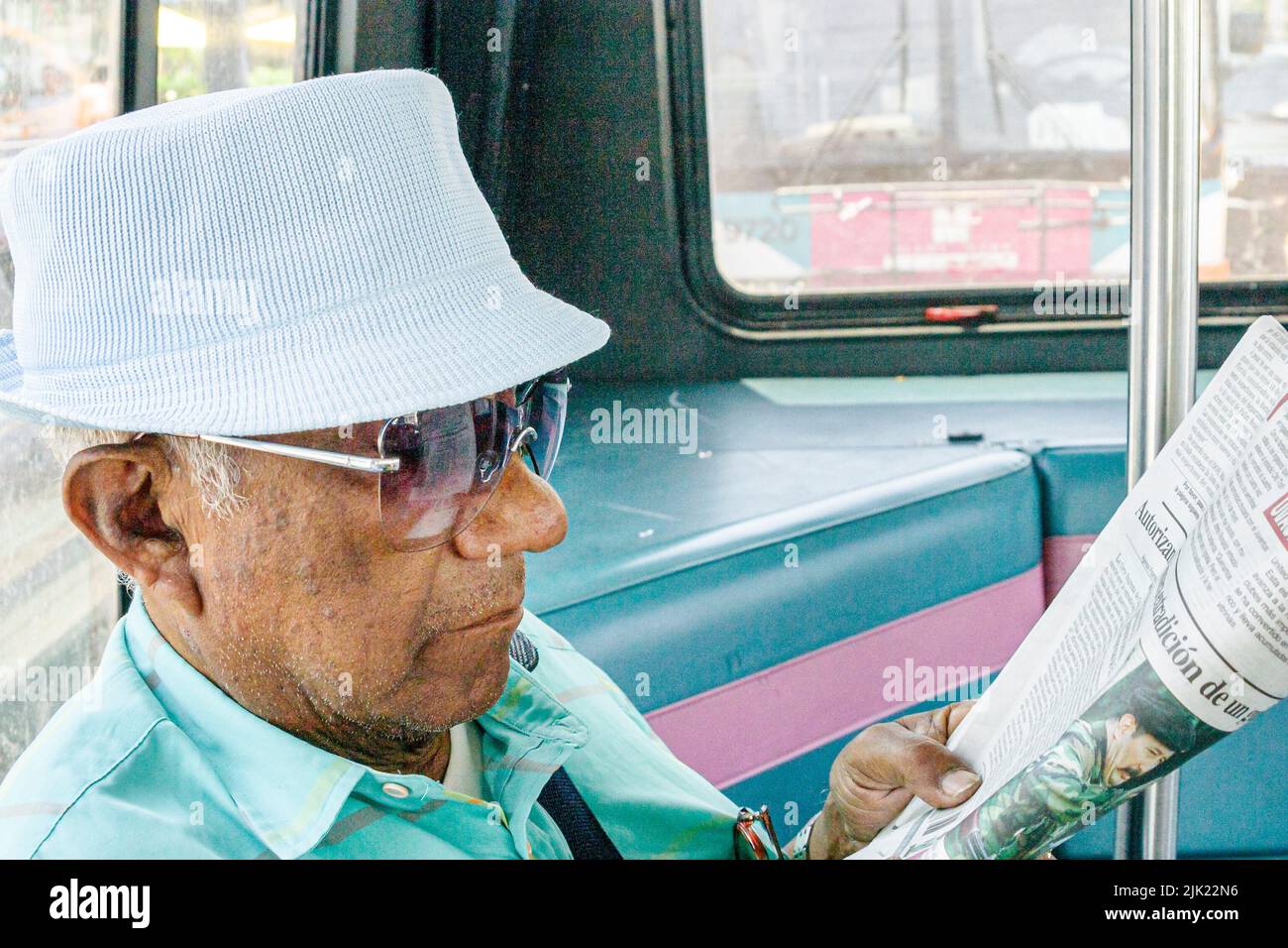 Miami Beach Florida,Miami-Dade Metrobus a bordo del interior del autobús público pasajeros jinetes, transporte hombre hispano leyendo el periódico Foto de stock