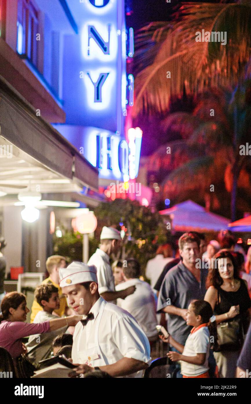 Miami Beach Florida, South Beach Ocean Drive noche vida nocturna al aire libre mesas comer fuera, restaurante Johnny Rockets Colony Hotel letrero de neón Foto de stock