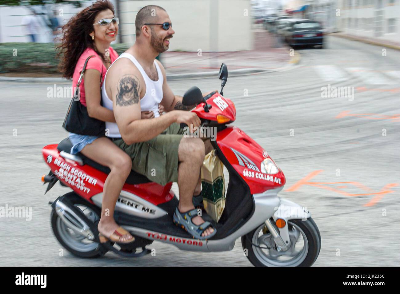 Miami Beach Florida,South Beach Ocean Drive Pareja parejas adultos hombre hombres hombre mujer mujer mujer mujer mujer mujer mujer, no cascos montar scooter tatuaje Foto de stock
