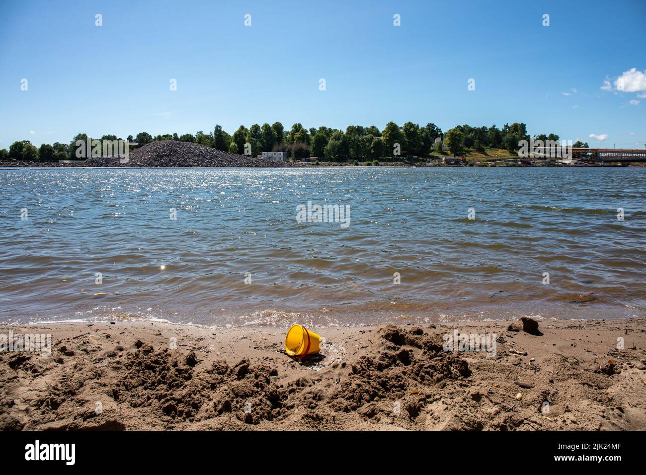 Cubo de juguete de arena de plástico amarillo abandonado en la playa Mustikkamaa de Helsinki, Finlandia Foto de stock