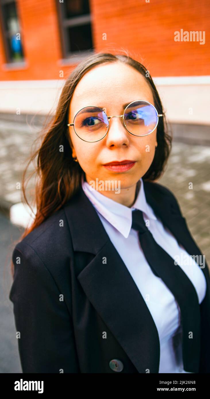 Mujer de negocios posando. Mujer joven con gafas, traje de negocios en la calle de la ciudad Foto de stock