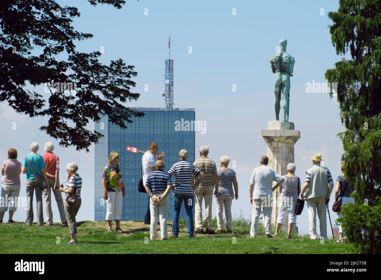 Céntrese en la Estatua de la Victoria y el rascacielos alto de Belgrado, la capital de Serbia, en primer plano en grupo de excursión borrosa Foto de stock