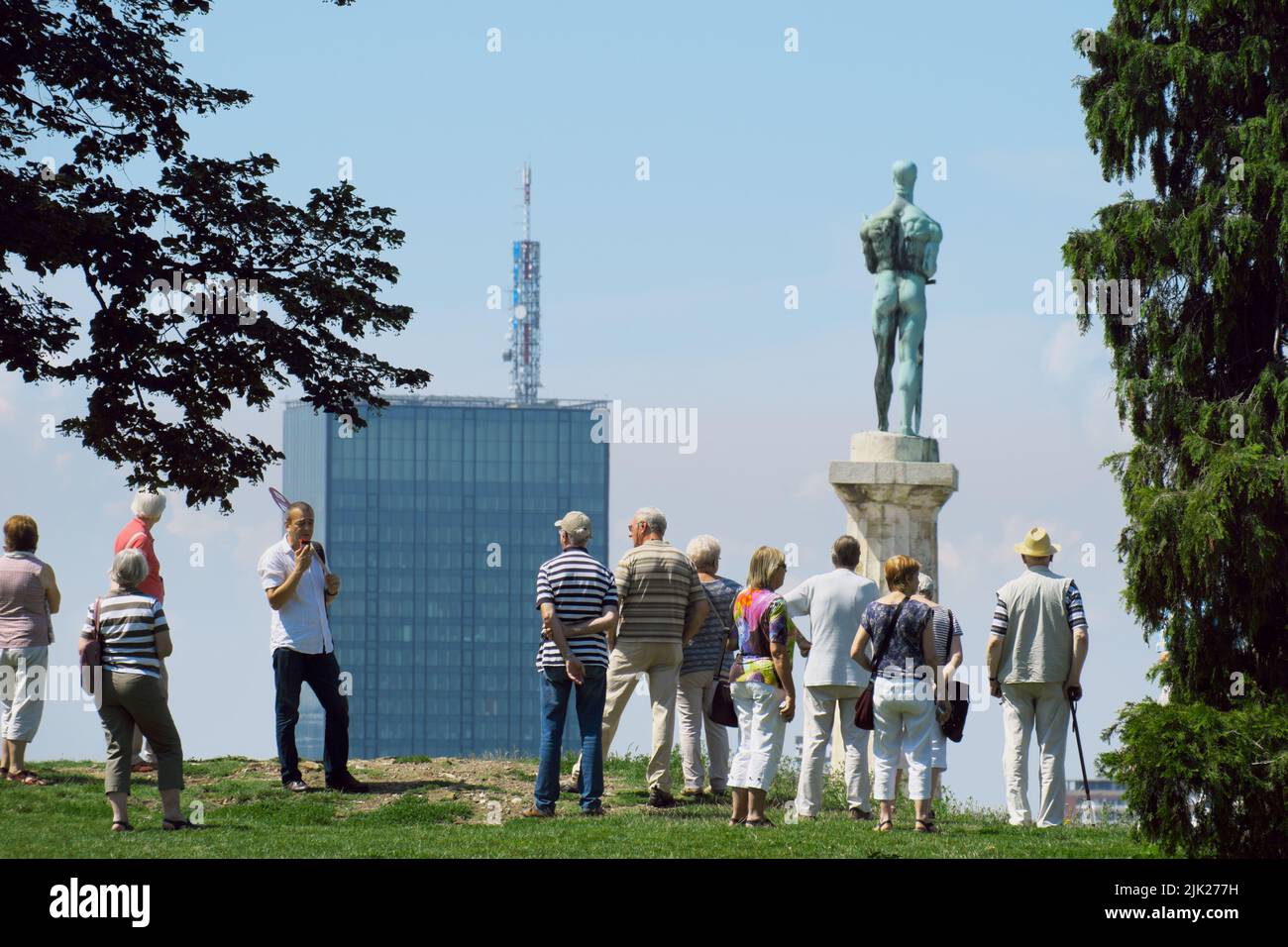 Tour en grupo en Belgrado, la capital de Serbia, en el fondo borrosa Estatua de la Victoria y alto rascacielos Foto de stock