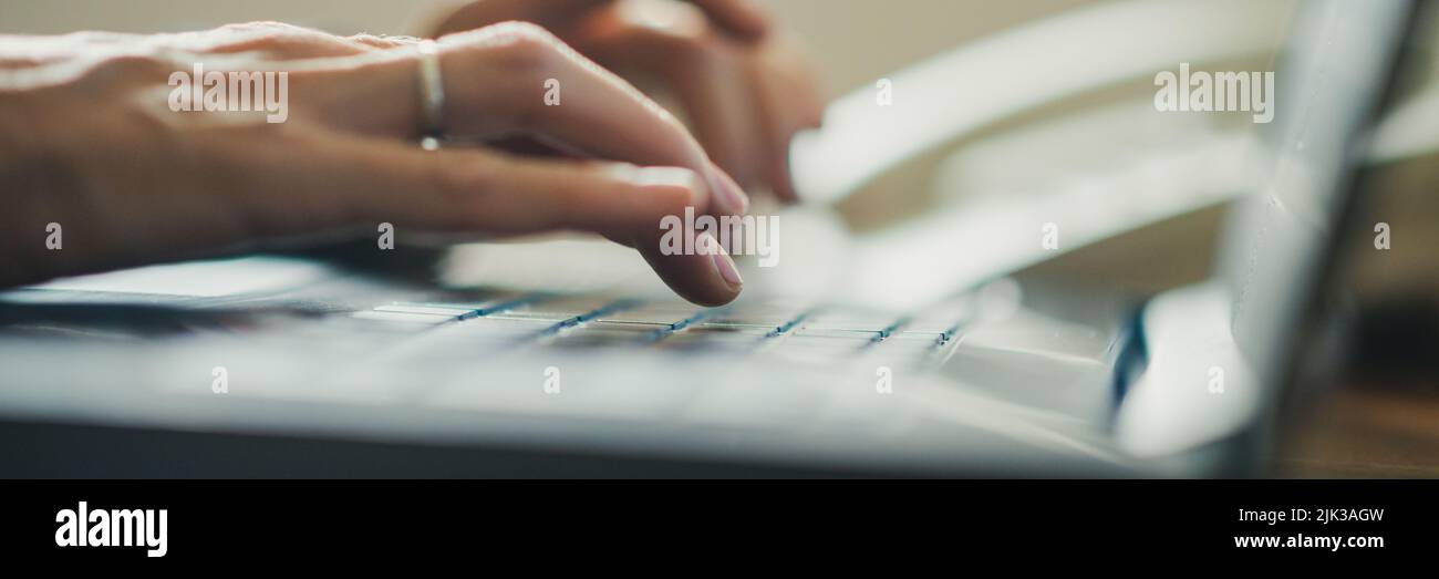 Vista en primer plano de las manos femeninas mecanografiando en el teclado de la computadora portátil con el foco en la mano delante y fondo borroso. Foto de stock