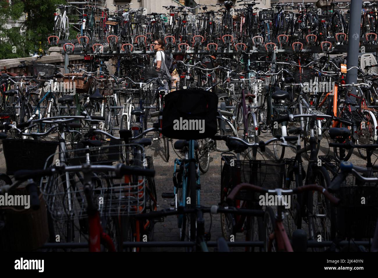 Una persona camina entre bicicletas almacenadas en estanterías fuera de la Estación Central de Copenhague en Copenhague, Dinamarca, 30 de julio de 2022. REUTERS/Andrew Kelly Foto de stock