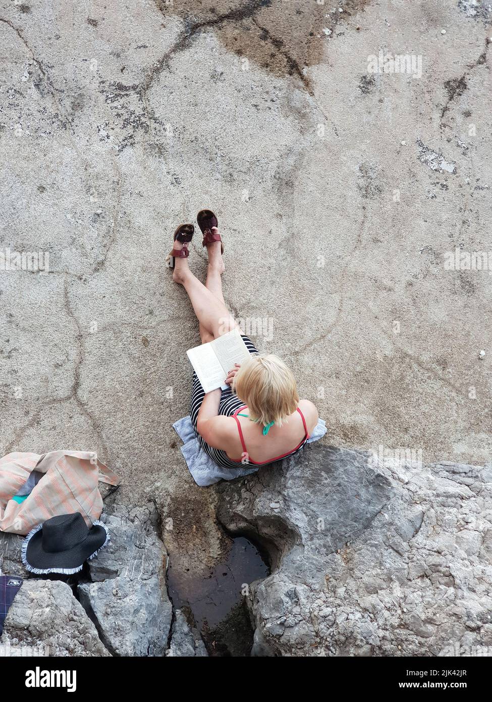Mujer joven leyendo un libro en una piedra Foto de stock