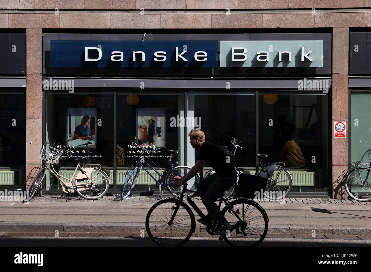 Una persona pasa en bicicleta por una sucursal de Danske Bank en Copenhague, Dinamarca, el 29 de julio de 2022. REUTERS/Andrew Kelly Foto de stock