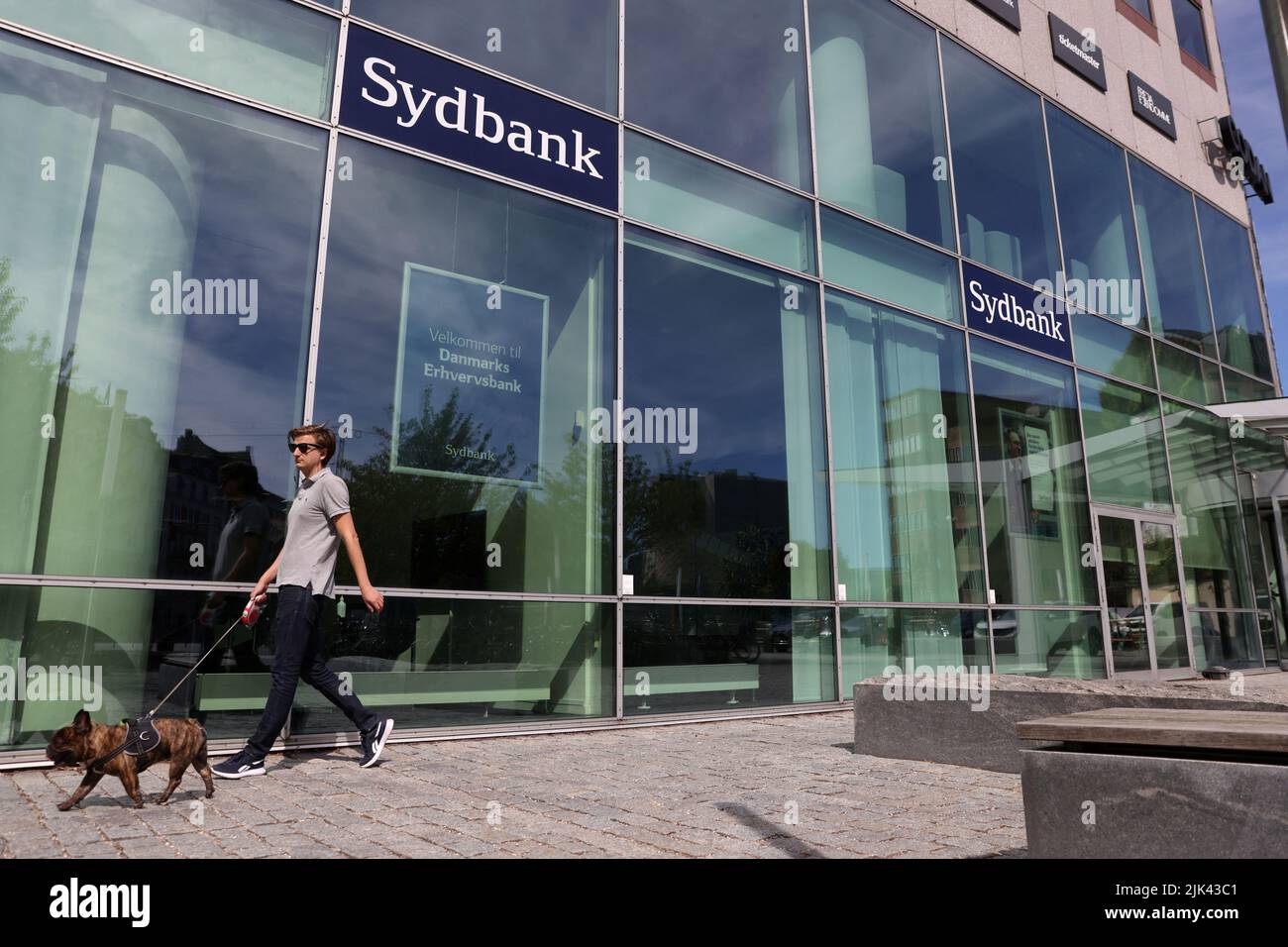 Una persona camina con un perro por las oficinas de Sydbank en Frederiksberg, Dinamarca, 29 de julio de 2022. REUTERS/Andrew Kelly Foto de stock