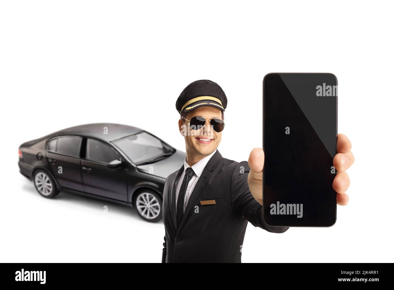 Conductor profesional sosteniendo un smartphone frente a un coche negro aislado sobre fondo blanco Foto de stock