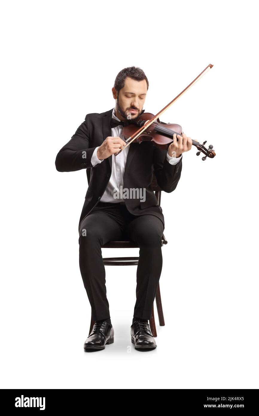 Retrato completo de un joven elegante sentado y tocando un violín aislado sobre fondo blanco Foto de stock