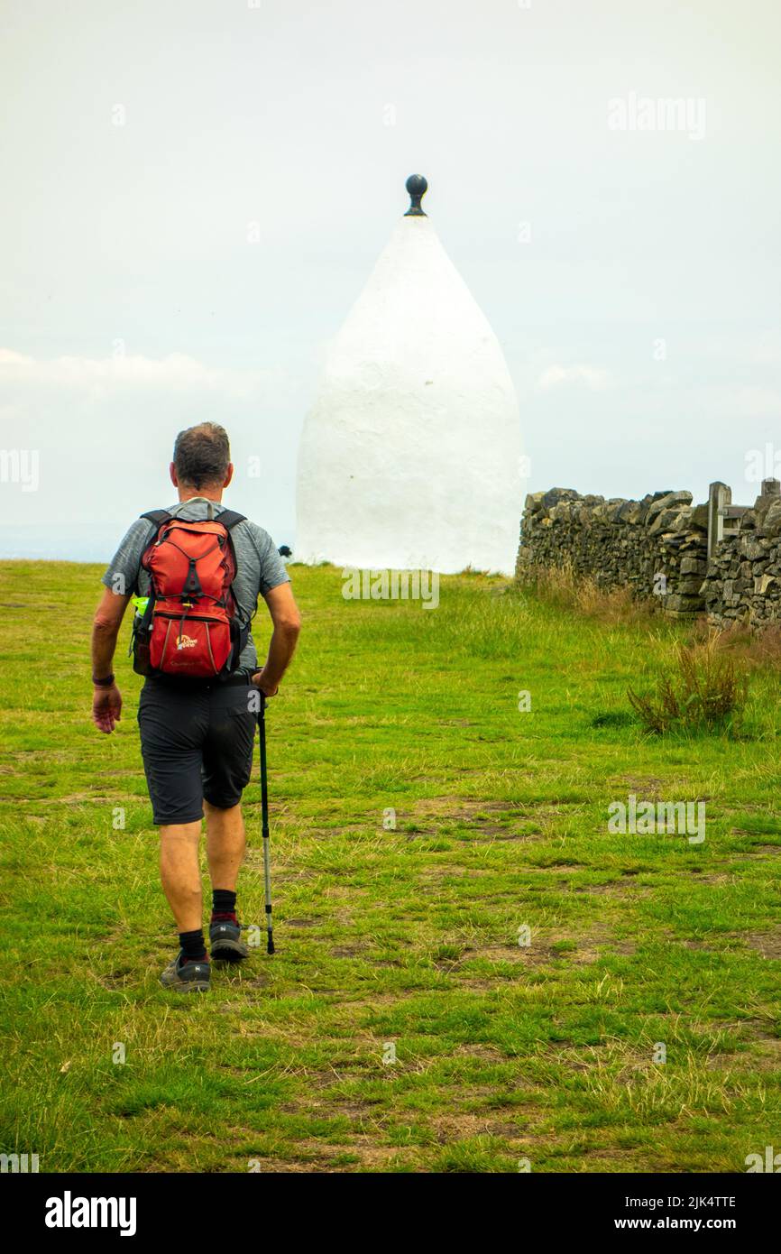 Hombre caminando por el punto de referencia de Cheshire, White Nancy, una estructura en el sendero de Gritstone en la cima de Kerridge Hill, Bollington Foto de stock