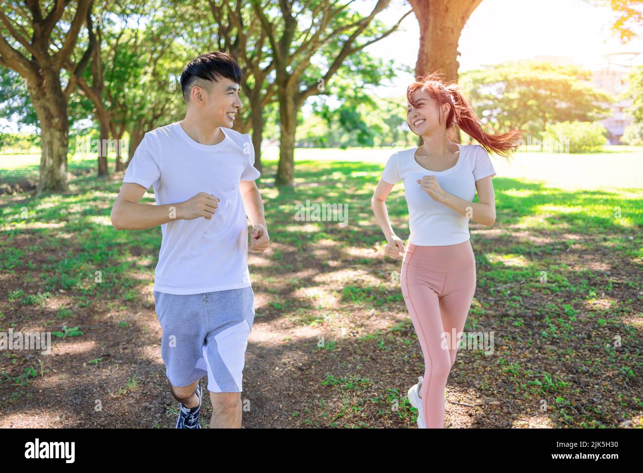 Feliz pareja joven corriendo en el parque en un día soleado Foto de stock