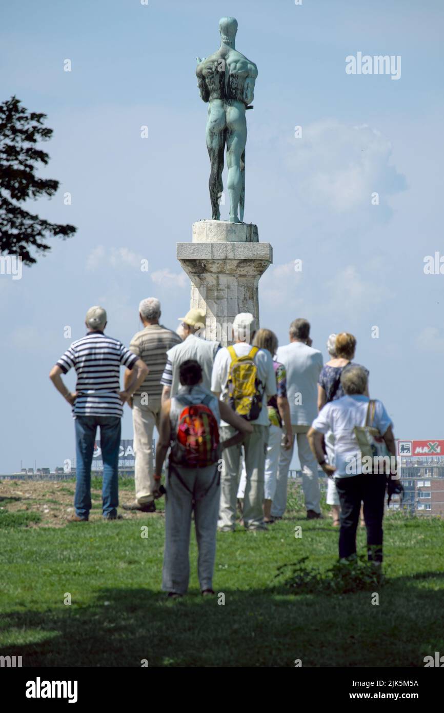 La Estatua de la Victoria en Belgrado, la capital de Serbia, en primer plano desdibujó a los turistas de un grupo de turistas mirando el panorama Foto de stock