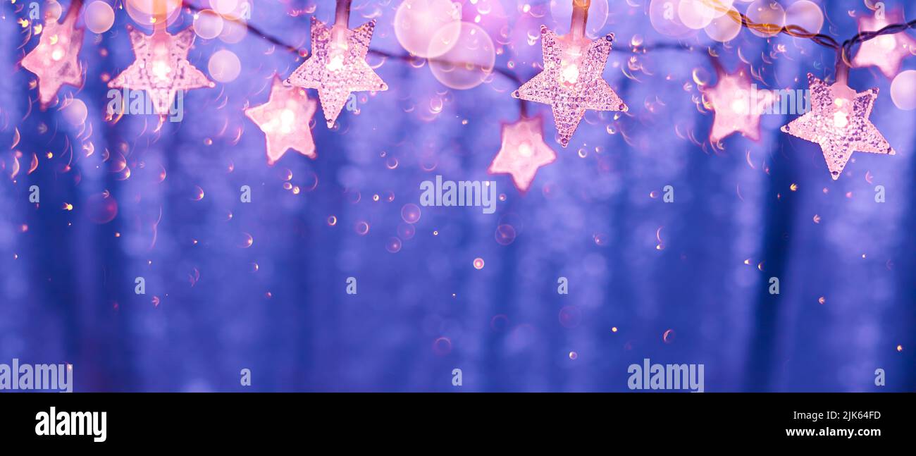 Luces de cuerda en forma de estrellas con luces bokeh sobre un fondo brillante en los colores de 2022 Foto de stock