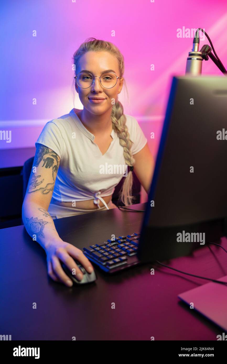 Retrato de Blond Gamer Girl con gafas jugando en línea Video Game en su ordenador Foto de stock