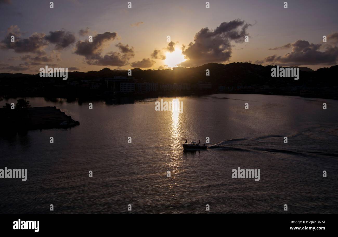 Un barco cruza el puerto mientras sale el sol en Castries Foto de stock