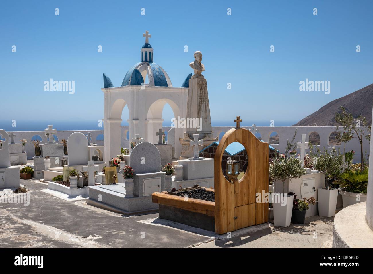 Hermosa iglesia encalada con cúpula azul, campanario y cementerio a pocos metros de la Iglesia de Agios Charalambos, Exo Gonia Santorini, Grecia. Foto de stock