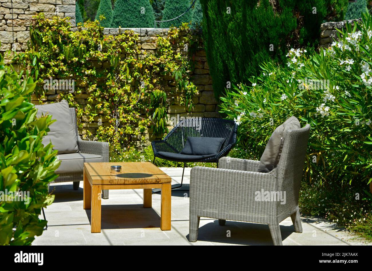 mobiliario de jardín en el patio-jardín, sillones y una mesa de café en el soleado patio Foto de stock