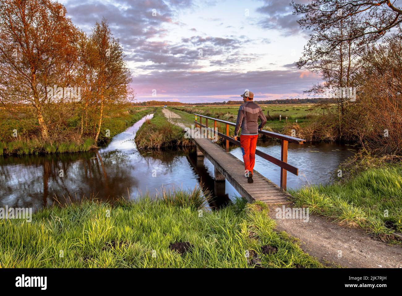 Caminante cruzando el puente sobre el río en el campo holandés Parque Nacional paisaje El Drentsche AA, Provincia de Drenthe, Países Bajos Foto de stock