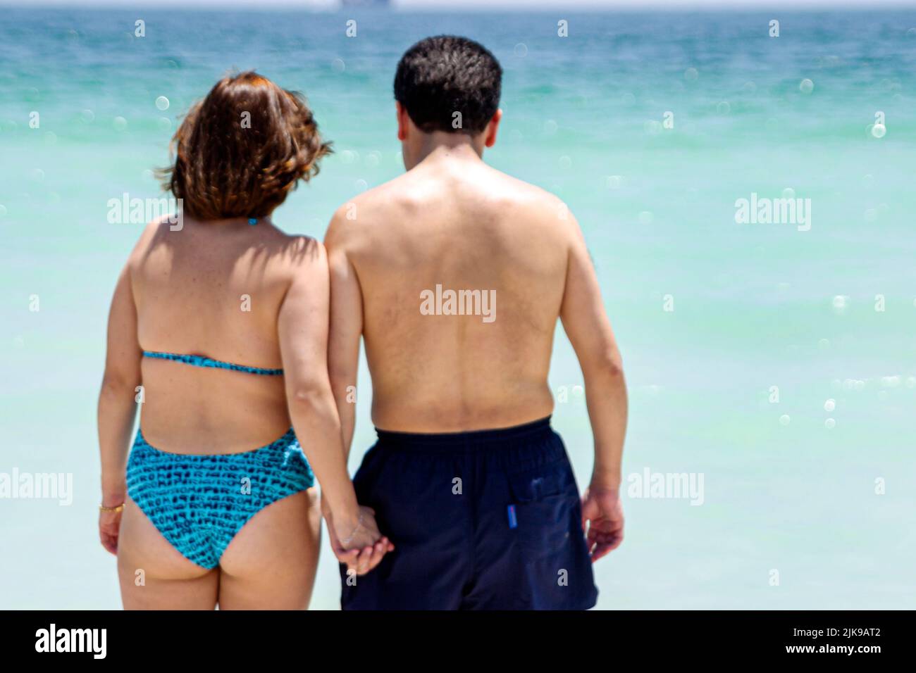 Miami Beach Florida, Atlantic Ocean Shore costa costa costa costa costa costa mar, parejas, adultos hombre hombre, mujer mujer teniendo las manos viendo surf Foto de stock