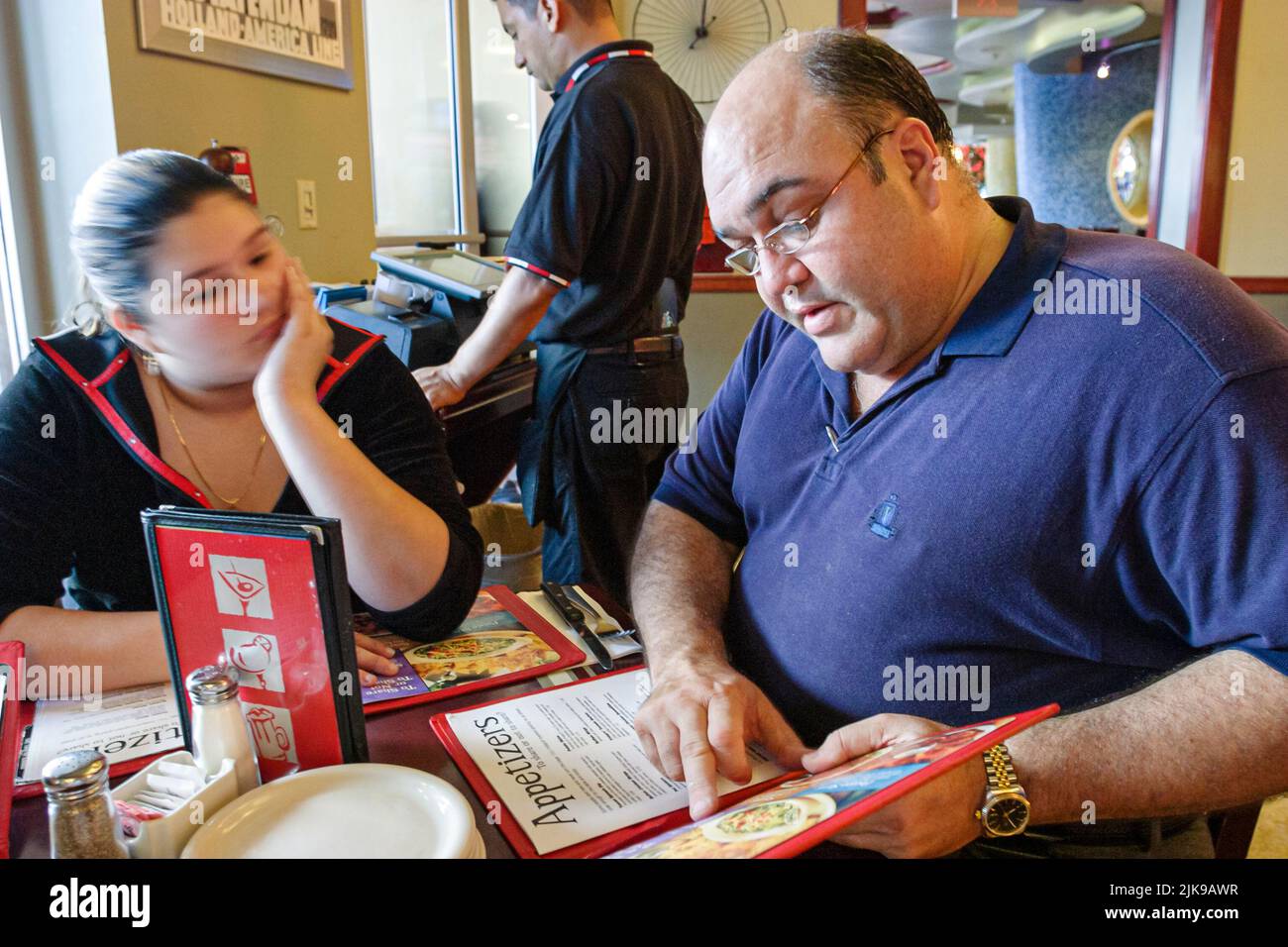 Miami Beach Florida, TGI Friday, restaurante comer fuera sobrepeso hispano cubano americano padre hija adolescente dentro del menú decidiendo elegir Foto de stock