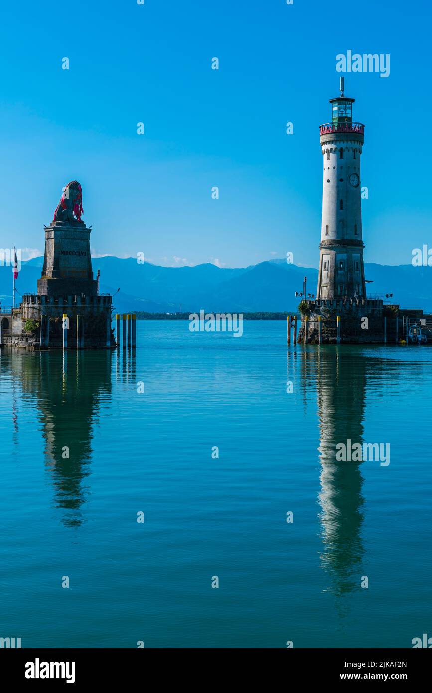 Alemania, el faro del puerto de la ciudad de Lindau y hermosas vistas a austria y las montañas de bregenz Alsp que se reflejan en el agua del lago bodensee Foto de stock