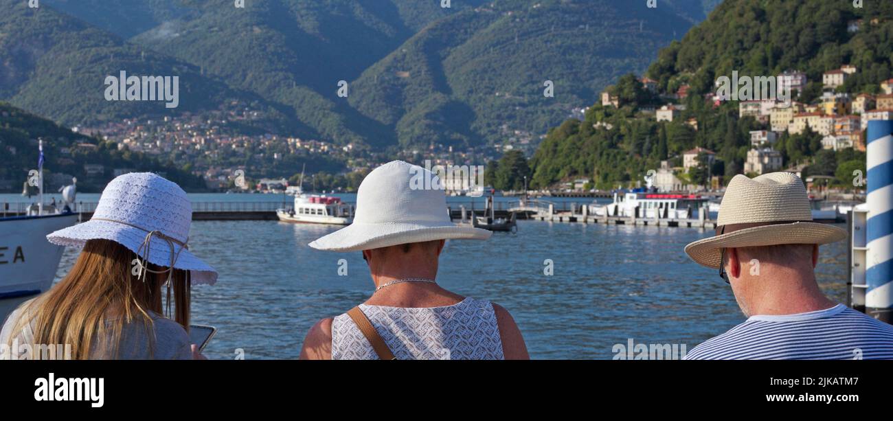 Turistas con sombrero de sol frente al Lago Como, Como, Italia Foto de stock