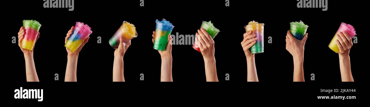 Manos de la cosecha de personas anónimas con coloridas y sabrosas bebidas dulces pulidas en vasos de plástico sobre fondo negro en un estudio moderno Foto de stock