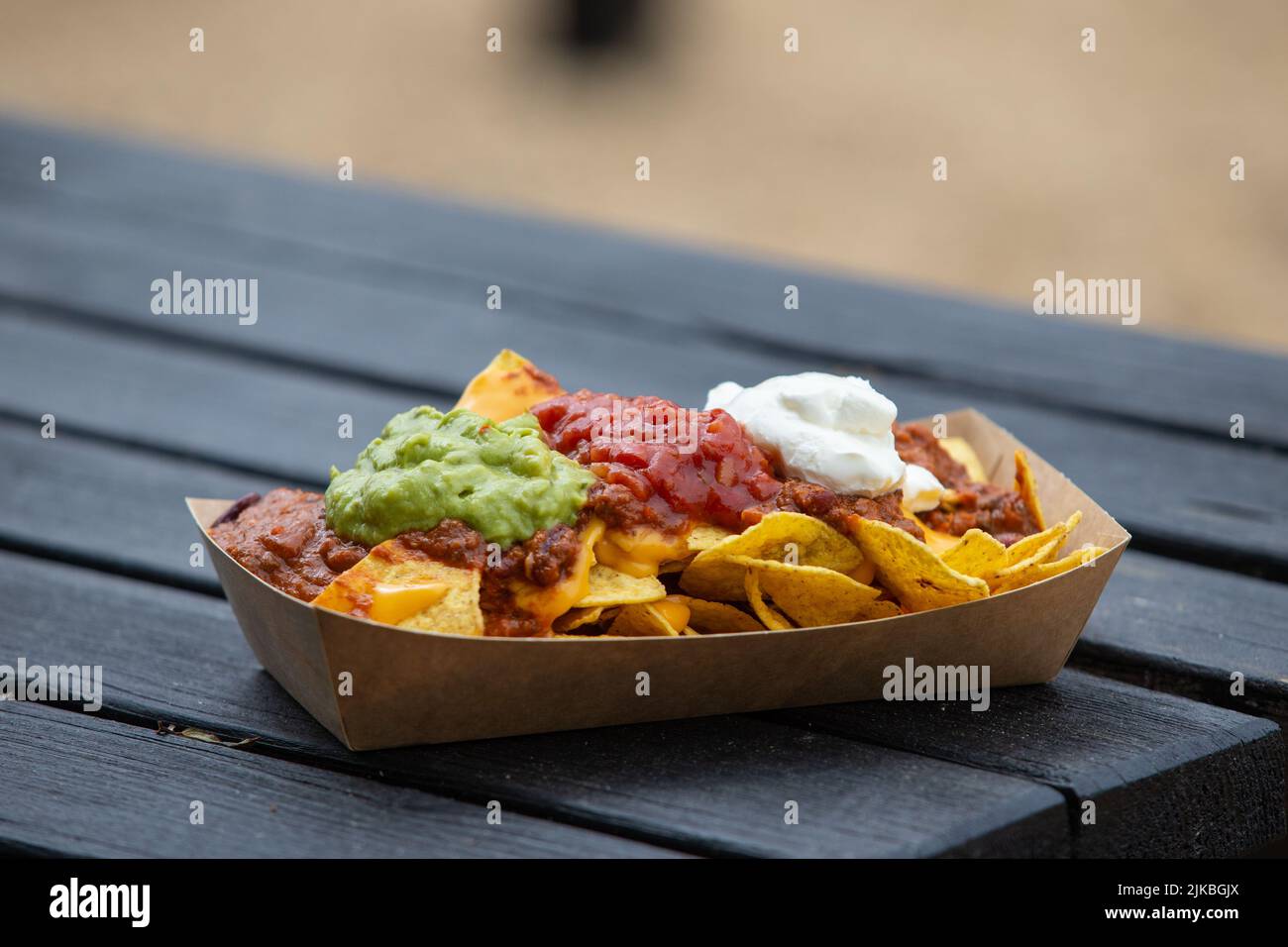 Porción de comida callejera, nachos de chile y queso con guacamole, salsa y crema agria Foto de stock