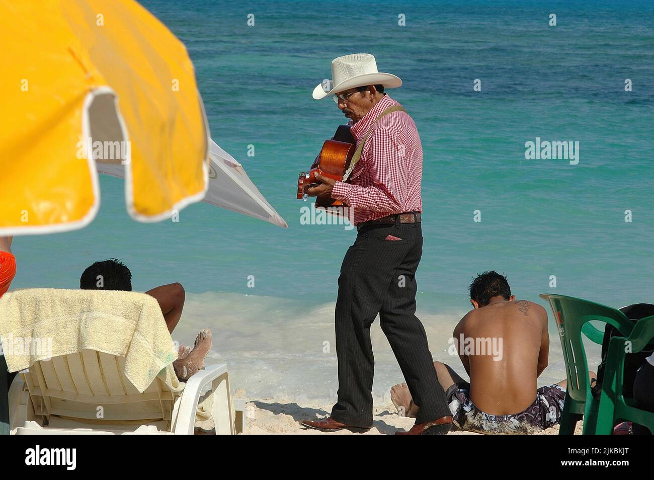 Un anciano mexicano camina, tocando la guitarra en una playa caribeña en la Riviera Maya de México. Enfoque selectivo Foto de stock