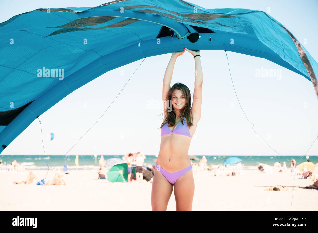 Hermosa kite surfing chica en traje de baño rosa bikini, sosteniendo una  cometa en su mano de pie en la playa para una buena sesión de kiteboarding  Fotografía de stock - Alamy